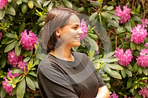 Profile portrait of a beautiful smiling woman in a black T-shirt against the background of a flowering bush