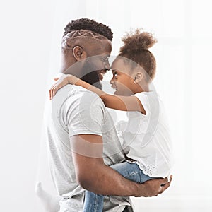 Profile portrait of black father and daughter bonding over white