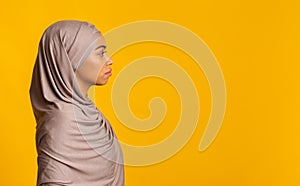 Profile portrait of black muslim woman in hijab over yellow background