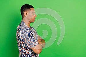 Profile portrait of calm concentrated young man folded arms look empty space isolated on green color background