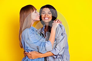Profile portrait of charming lovely ladies hugging kiss cheek closed eyes isolated on yellow color background