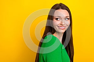 Profile portrait of cheerful nice girl beaming smile look interested empty space isolated on yellow color background