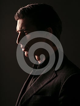 Profile portrait of a confident business man dressed in black stylish suit portrait against a dark background