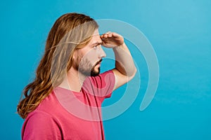 Profile portrait of focused nice young man arm touch forehead look away empty space isolated on blue color background