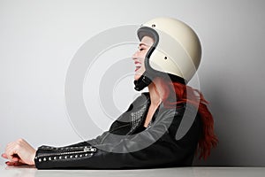 Profile portrait of happy young biker woman wears helmet and leather jacket.