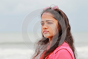 A profile portrait head shot of a beautiful young Indian woman standing alone on the shores of Chennai in the evening