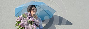 Profile portrait romantic teenage girl with bouquet of lilacs, with umbrella on gray wall background. Outdoor, copy space,