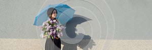 Profile portrait romantic teenage girl with bouquet of lilacs, with umbrella on gray wall background. Outdoor, copy space,