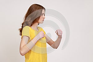 Profile portrait of serious concerned woman of young age holding clenched fists up ready to boxing