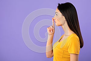 Profile portrait of woman puting finger on lips