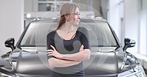 Profile portrait of young caucasian girl looking away and smiling as standing at car dealership. Beautiful woman posing