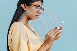 Profile portrait of young indian woman in glasses using phone