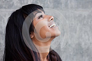 Profile portrait of young Indian woman laughing and looking up