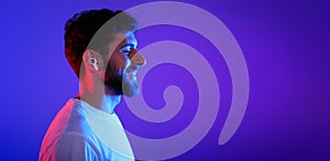 Profile portrait of young man wearing wireless earphones enjoying music