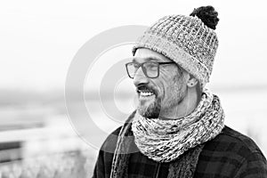 Profile portrait of young smiling man in glasses and flannel jacket. Knitted hat and scurf