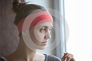 Profile portrait of a young woman alone looking out window.