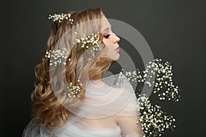 Profile portrait of young woman with blonde curly hairdo and white flowers