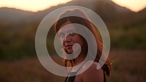 A profile portrait of a young woman posing and smiling in nature