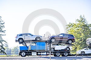 Profile of the running blue big rig classic car hauler semi truck transporting cars on the modular semi trailer