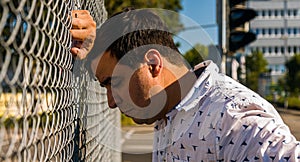 Profile of Sad Caucasian Man Leaning Forehead on Fence