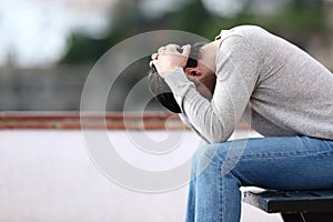 Profile of a sad man complaining sitting on a bench