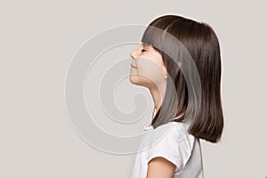 Profile of serene little girl isolated on grey studio background