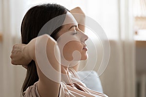 Profile serene young woman relaxing with hands behind head