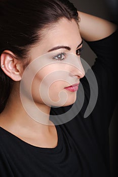 Profile shot of a beautiful young model holding her hair up