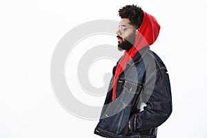 Profile shot of dreamy and thoughtful handsome stylish african american guy in denim jacket over red hoodie, looking