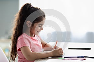 Profile Shot Of Little Smiling Girl Drawing With Colorful Pencils At Home