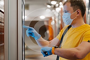 Profile shot of man checks time on watch, uses touch screen in protective rubber gloves, avoids spreading coronavirus, pandemic