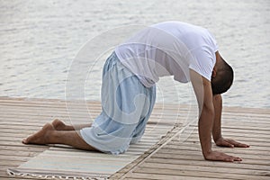 Profile shot of mature man meditating in lotus position on pier against lake