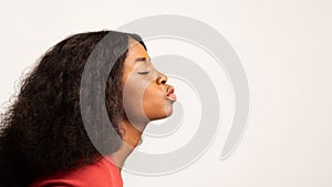 Profile Shot Of Young Black Woman Pouting Lips Over White Studio Background