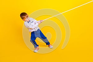 Profile side full length photo of little schoolkid boy pull heavy rope tug war game  on vivid color background