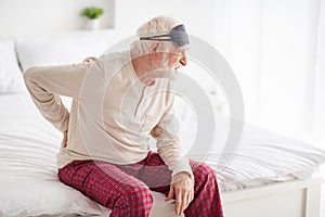 Profile side photo of aged man pensioner sit bad hand on spine spasm hurt spine unhappy unwell look empty space indoors