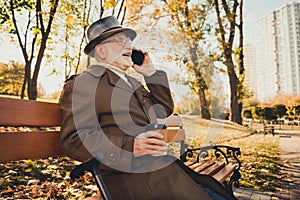 Profile side photo of grey white hair positive old man enjoy rest town park autumn outside relax sit bench call talk