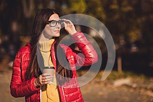 Profile side photo of trend modern girl enjoy october fall park stroll walk hold drink cappuccino takeout coffee buy