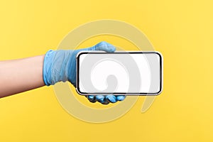 Profile side view closeup of human hand in blue surgical gloves holding and showing smart phone empty horizontal display