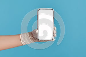 Profile side view closeup of human hand in white surgical gloves holding and showing smart phone empty display