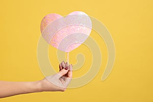 Profile side view closeup of woman hand holding heart pink love stick, showing romantic feelings.