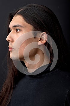 profile side view of confident man with black long straight hair looking away, isolated