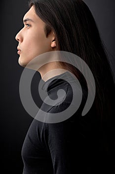 profile side view of handsome confident man with black long straight hair looking away