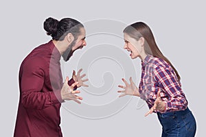 Profile side view portrait of angry bearded man and woman in casual style standing, looking and screaming at each other