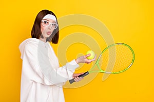 Profile side view portrait of attractive amazed girl fan amateur playing tennis isolated over bright yellow color