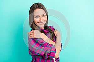 Profile side view portrait of attractive cheerful girl hugging herself copy space isolated over bright teal green color