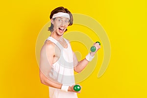 Profile side view portrait of attractive cheerful guy lifting small light dumbbell isolated over bright yellow color