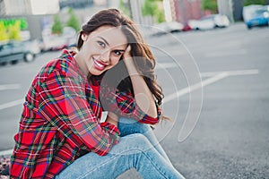 Profile side view portrait of attractive cheerful wavy-haired girl sitting on parking spending weekend streetstyle
