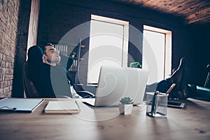 Profile side view portrait of his he handsome stylish trendy guy sitting in chair having free time legs on table