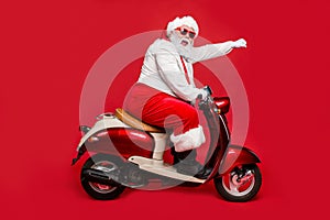 Profile side view portrait of nice bearded cheerful funny funky purposeful Santa Claus riding moped hurry up shopping