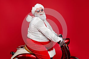 Profile side view portrait of nice bearded cheerful funny funky Santa St Nicholas father riding motor bike delivering